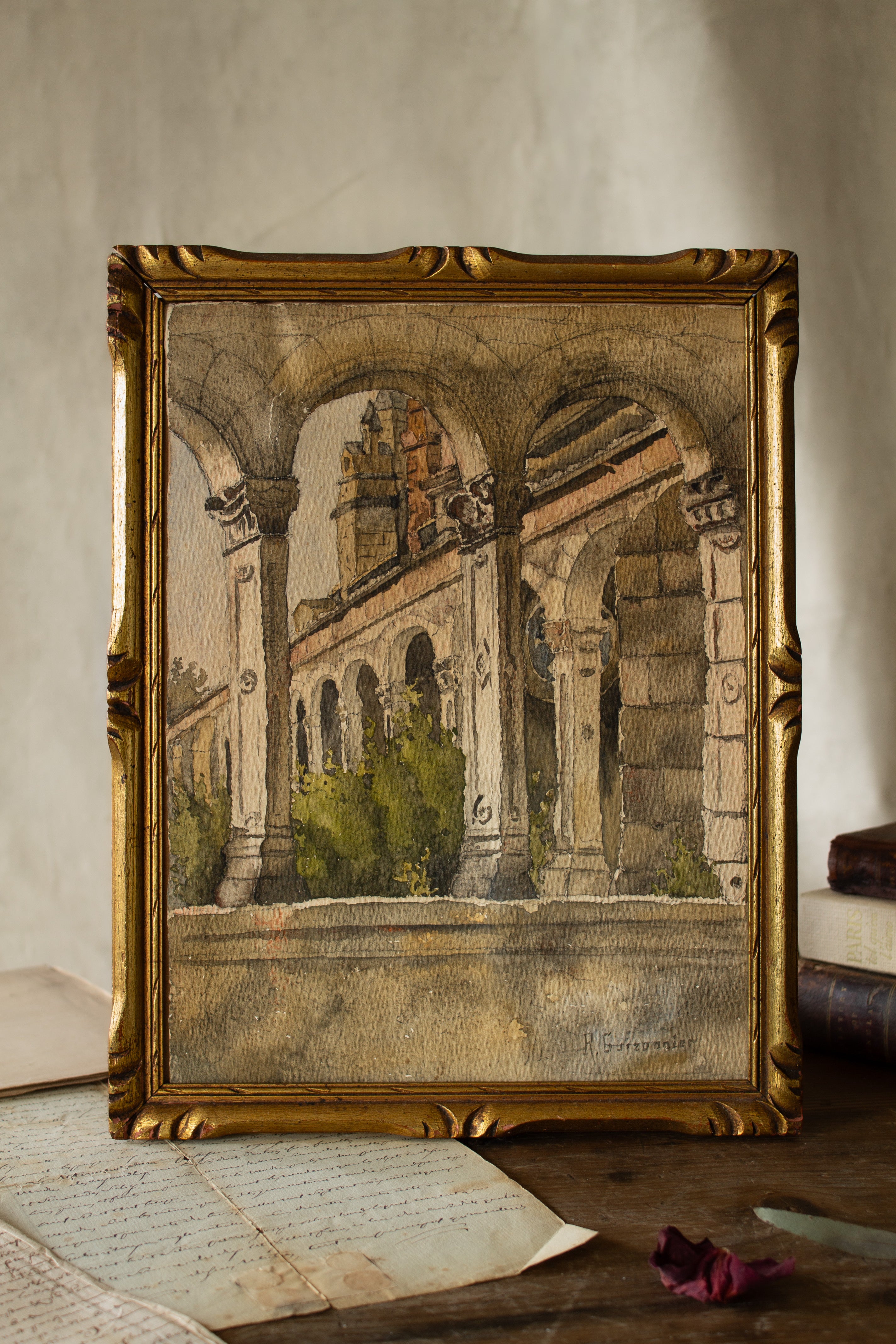 Signed French architectural watercolor of an arched courtyard with columns, warm stone tones, textured paper, and an older giltwood frame
