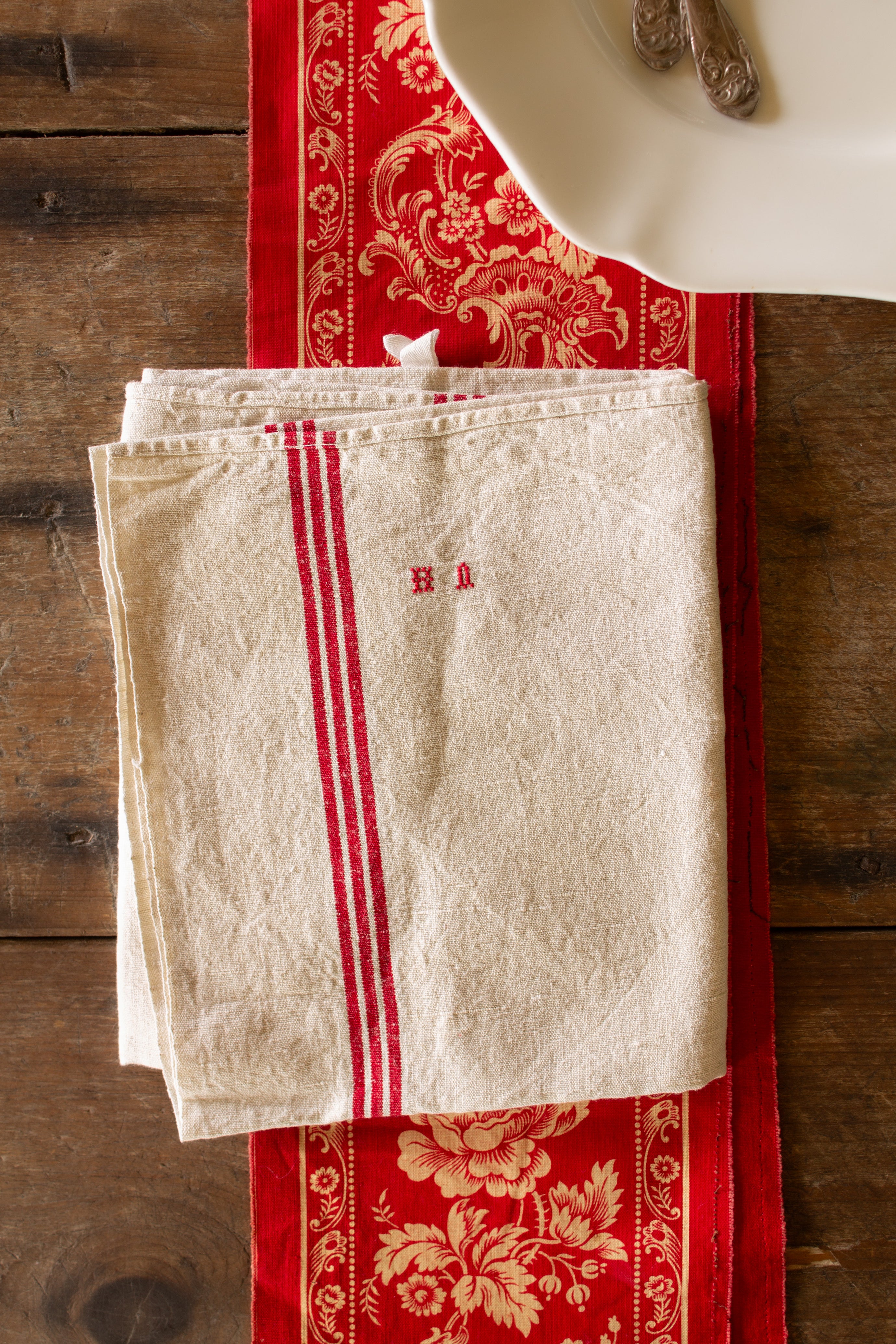 Antique French red stripe linen torchon with hand-embroidered HA monogram, hanging loops, and natural cream linen ground.