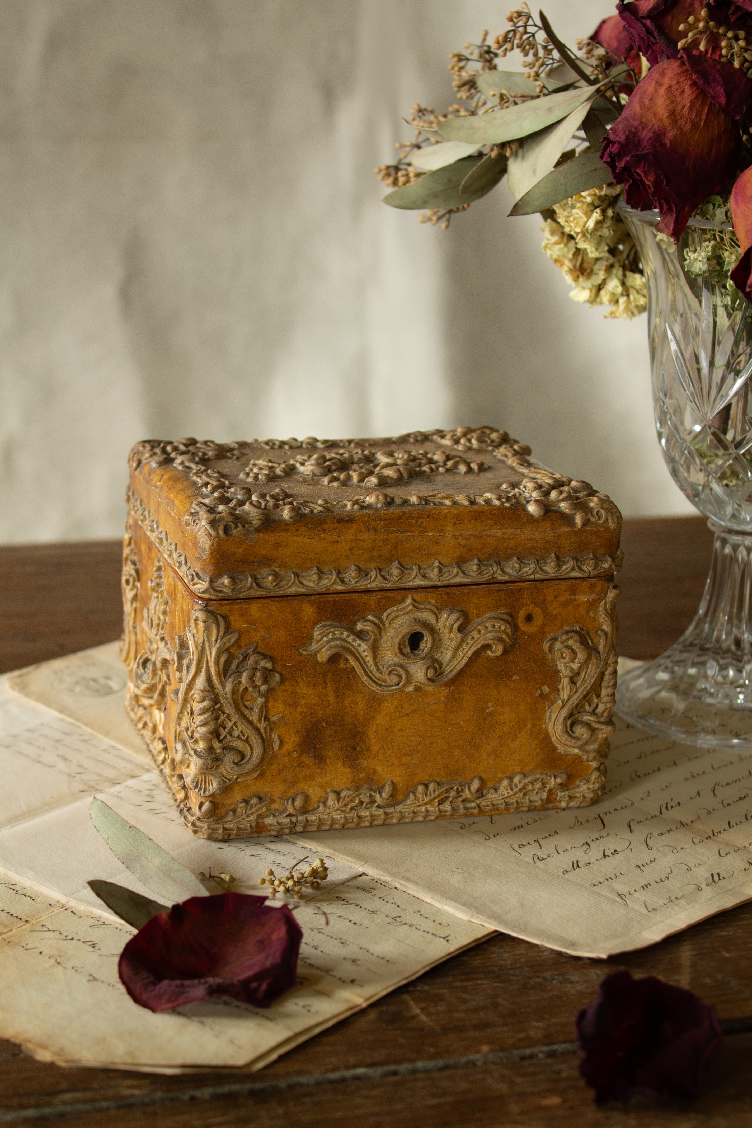 Antique French Rococo Revival boudoir box with amber paper-covered surface, raised floral ornament, metallic paper-lined interior, lock hardware, and aged patina