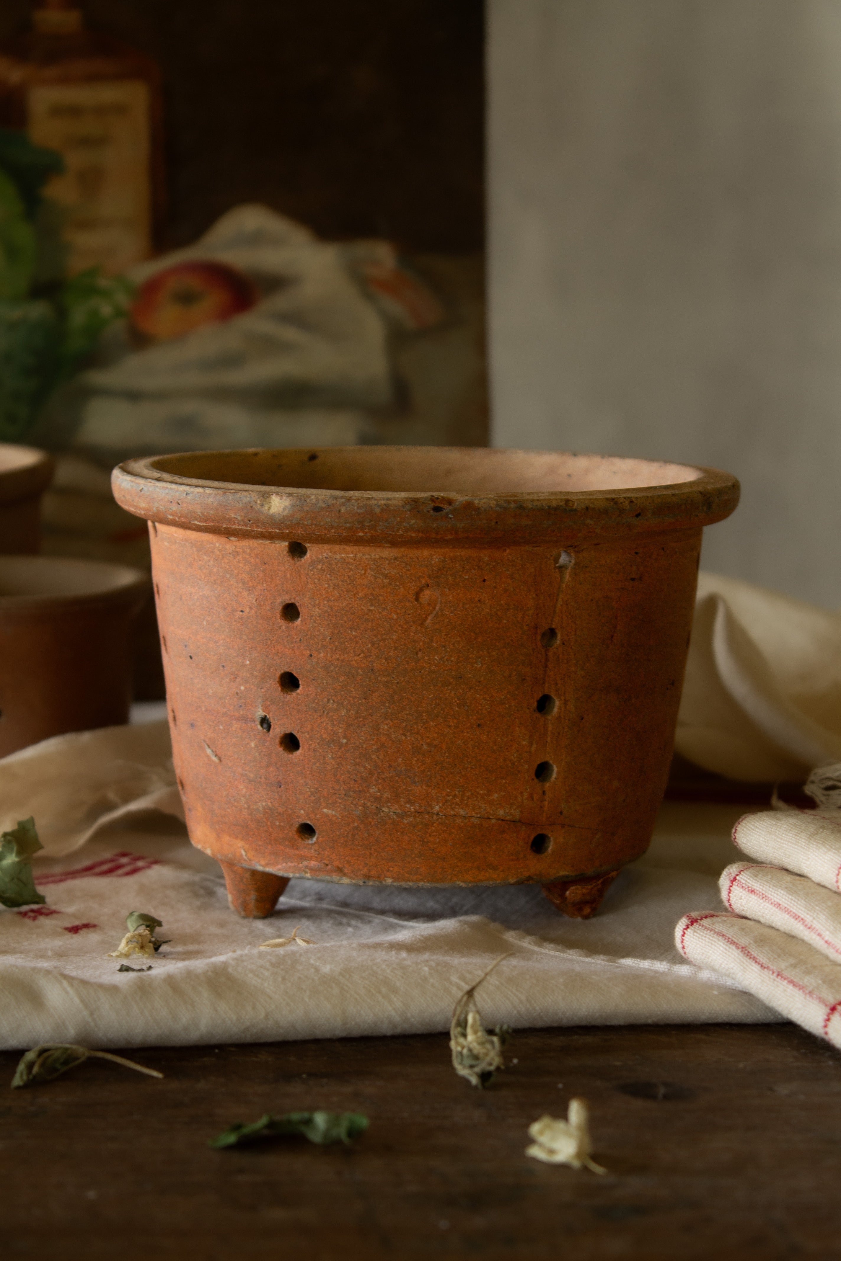 Antique French terracotta three-footed faisselle cheese mold with hand-pierced drainage holes and warm aged earthenware surface.