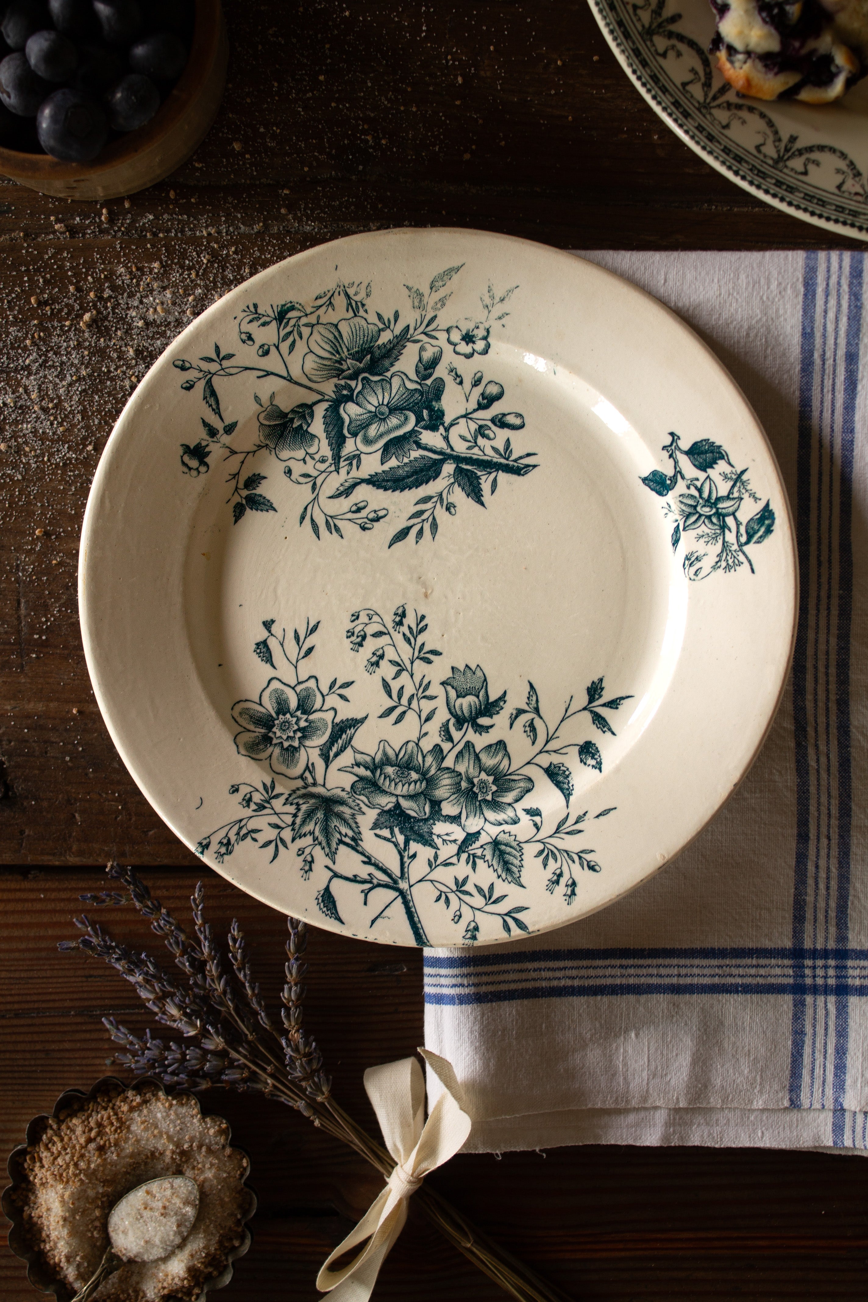 Antique French Terre de Feu de Grigny plate with aged blue-green botanical floral sprays on a warm cream ground.