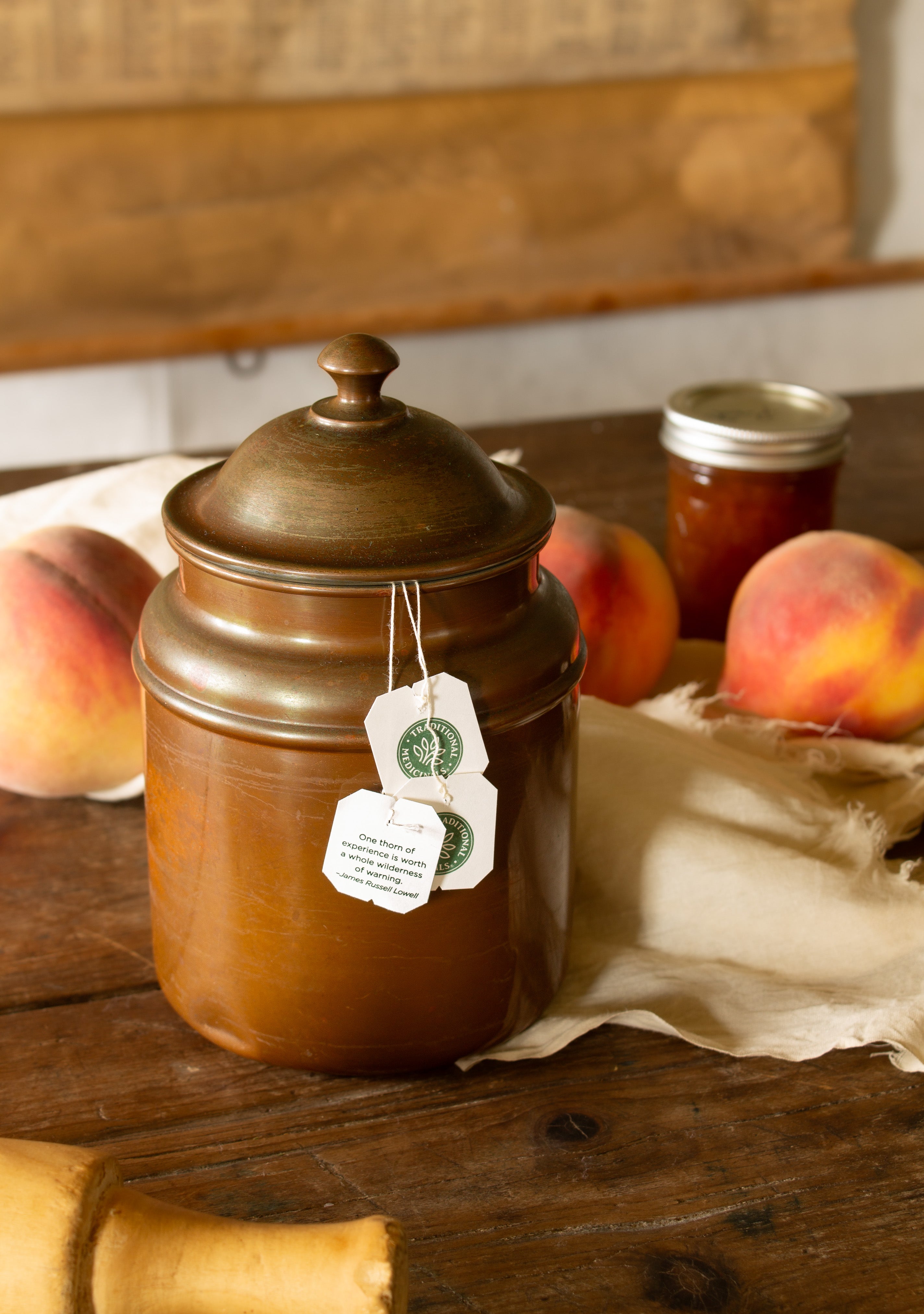Vintage copper-plated lidded kitchen canister with domed lid and warm aged patina, styled with tea bags and peaches.