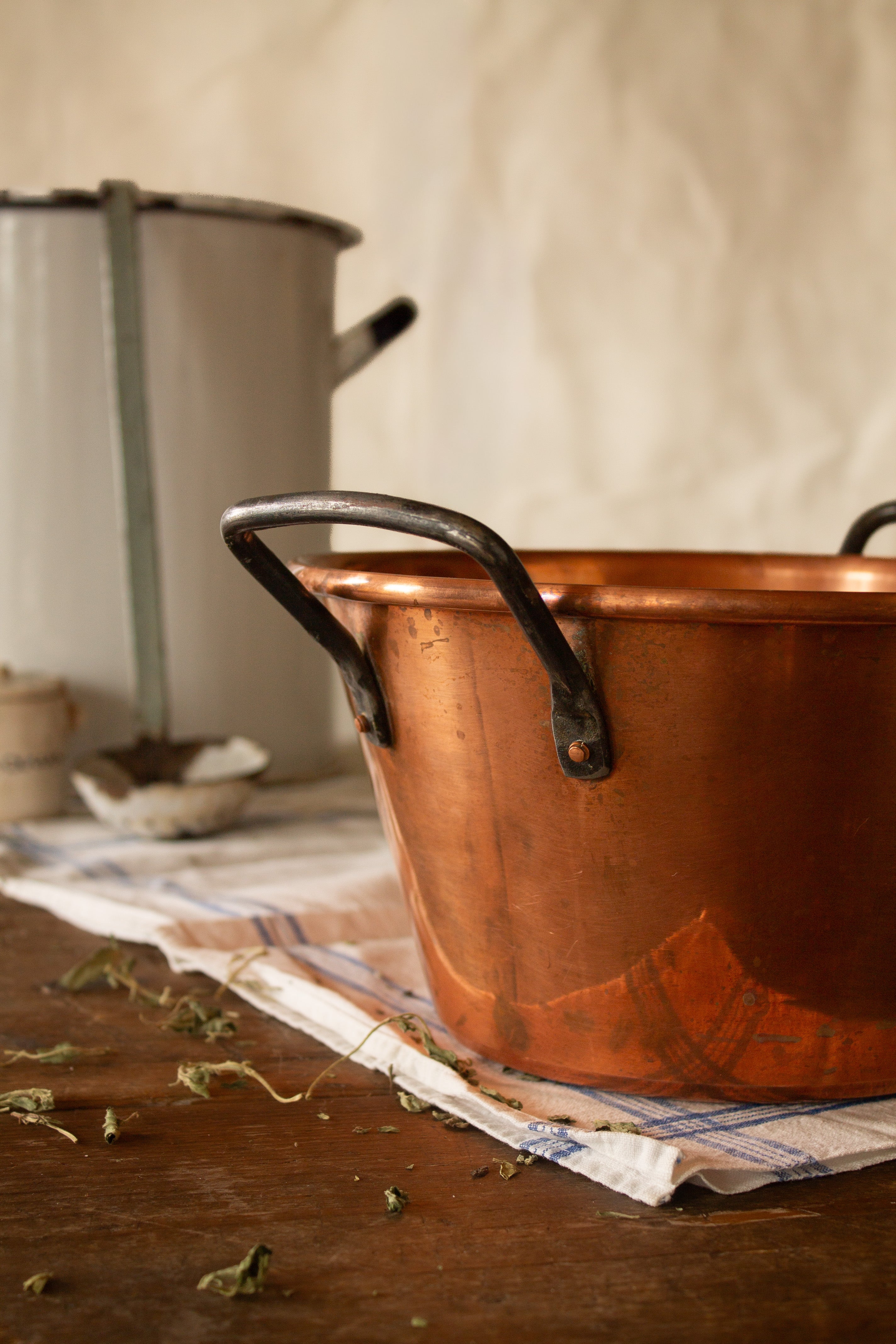 Vintage French Baumalu copper jam pot with iron handles, stamped Made in France, styled on an antique wooden table.