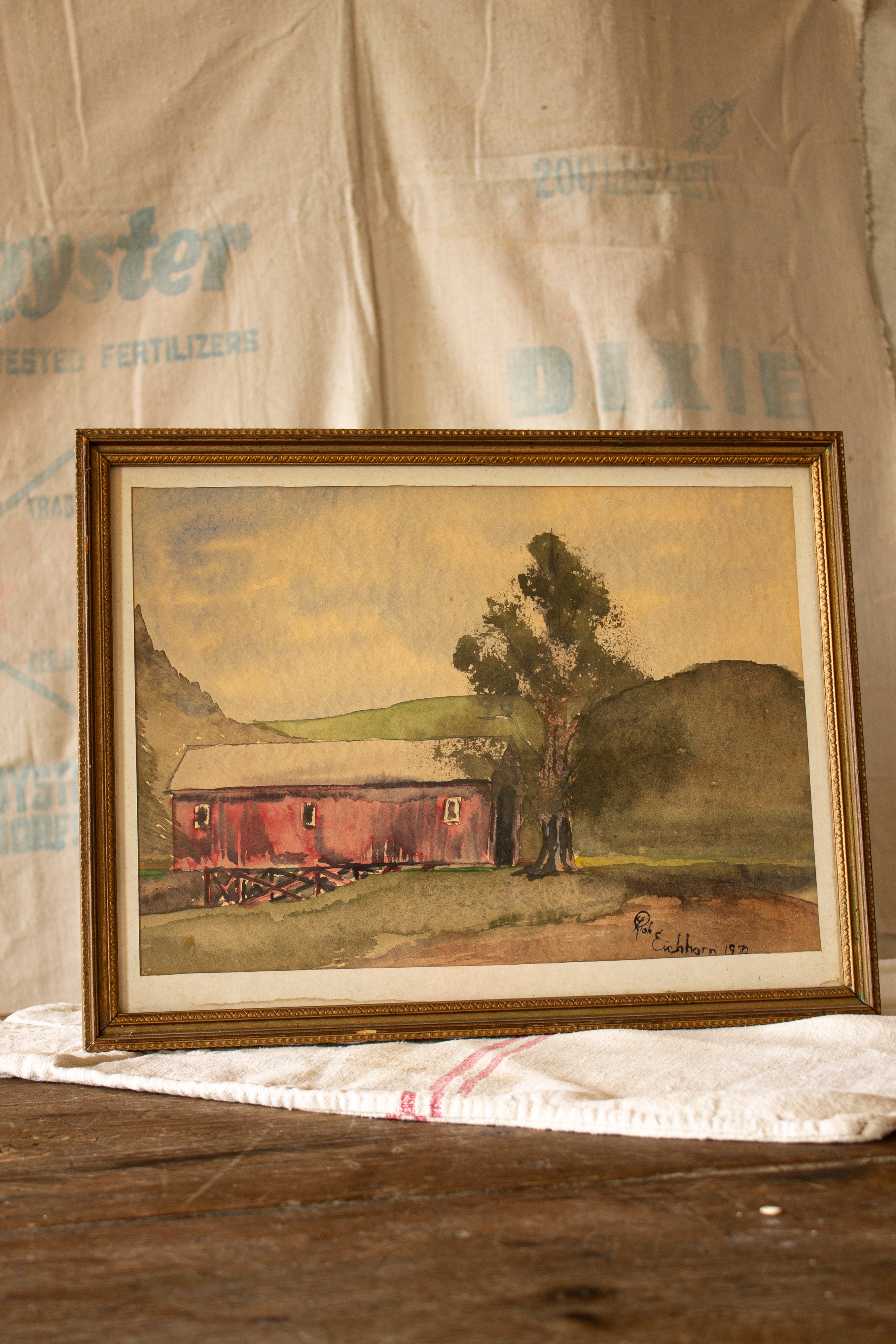 Vintage signed Eichhorn 1970 watercolor red barn landscape in gold-toned frame, matted under glass and ready to hang.