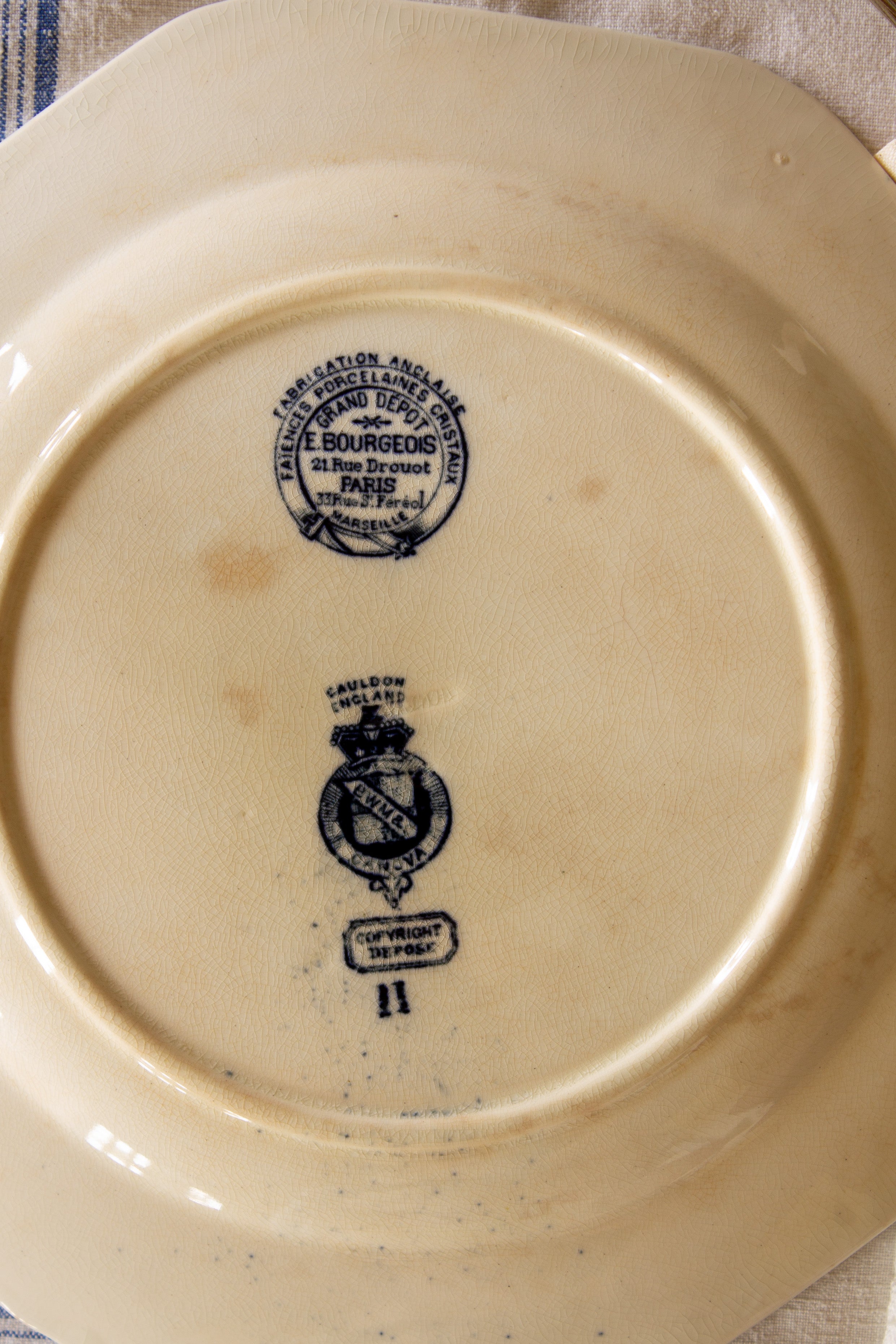 Close-up of Cauldon England Canova and E. Bourgeois Grand Dépôt Paris marks on the back of the antique plate.