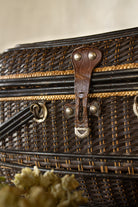 Close view of the worn leather latch and metal hardware on an antique wicker fishing creel basket.