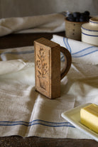 Antique French wooden butter stamp with carved floral design and distinctive D-shaped handle.