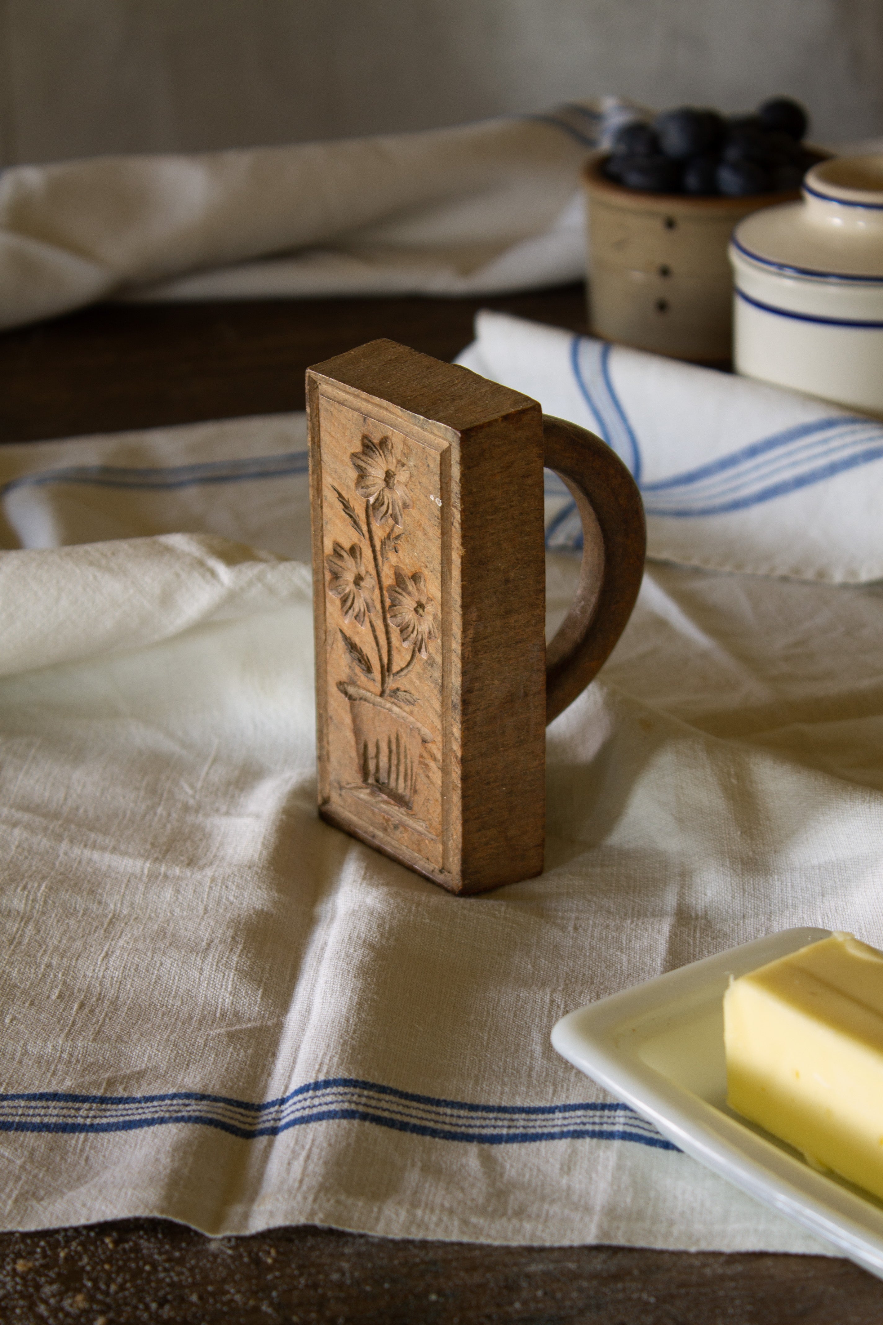 Antique French wooden butter stamp with carved floral design and distinctive D-shaped handle.