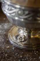 Detail of the pedestal foot and floral medallion decoration on a French Gallia silver-plated sugar caster.