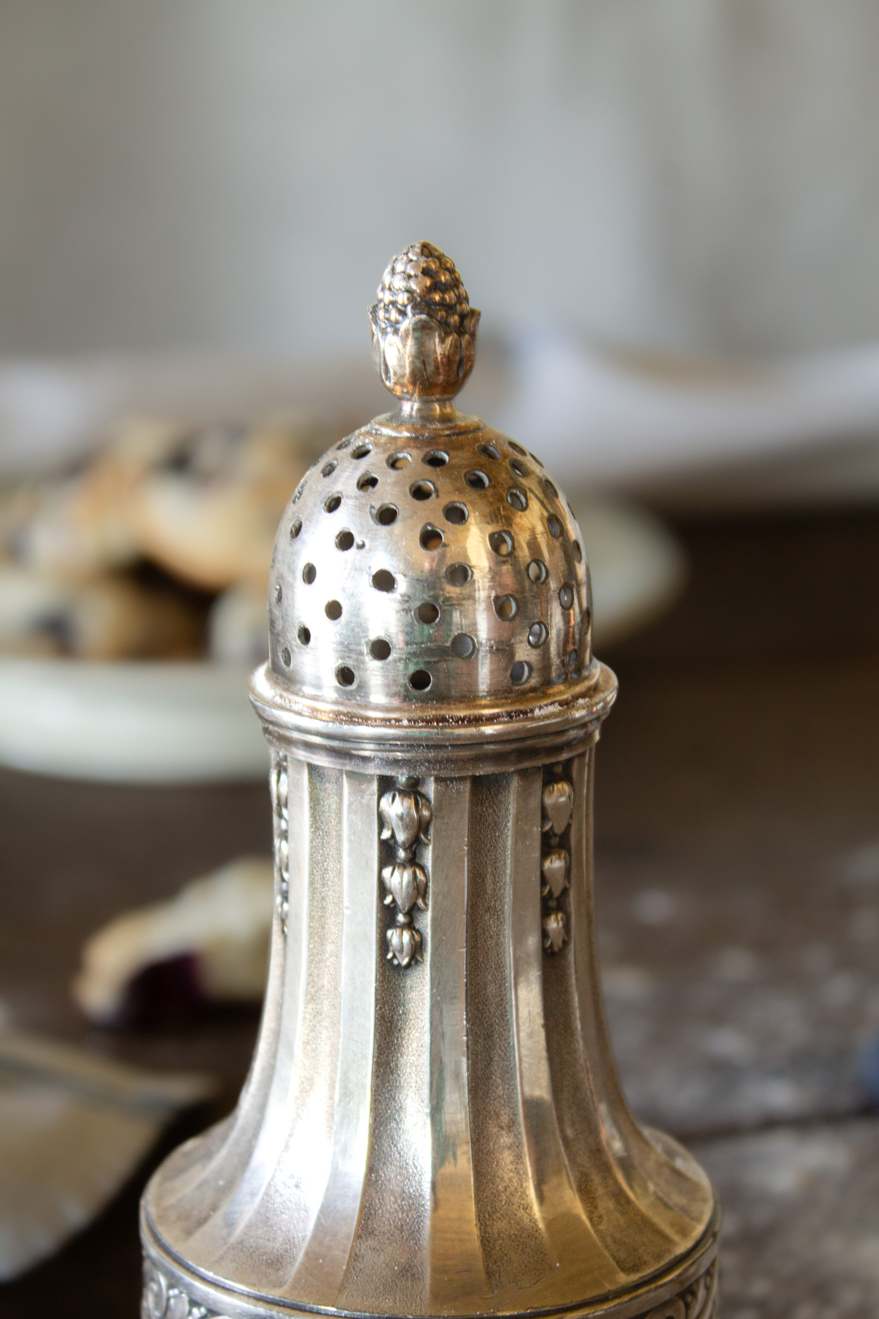 Close view of the pierced dome lid and floral finial on a French Gallia silver-plated sugar caster.
