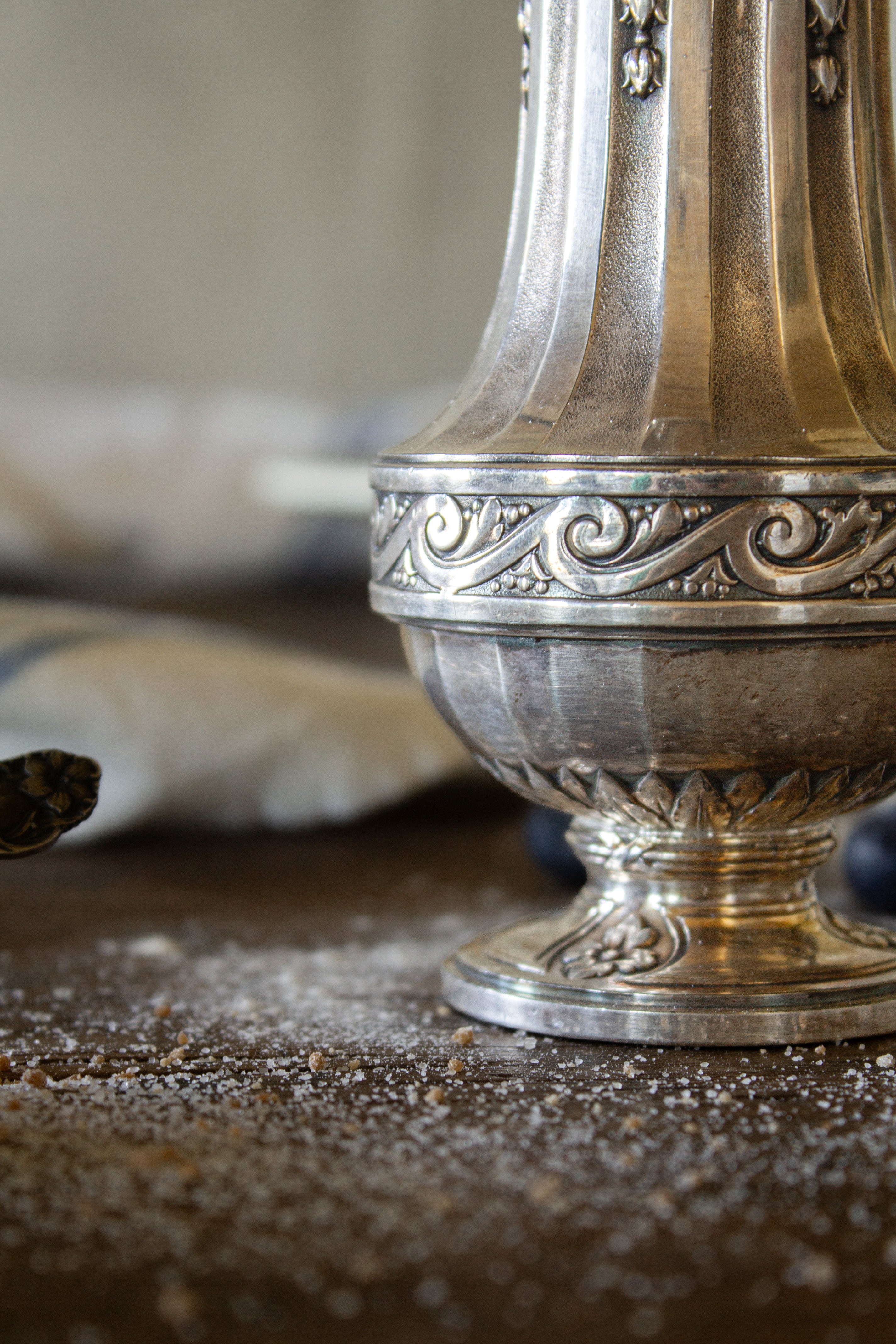 Detail of the raised scrollwork band and fluted body on a French Gallia silver-plated sugar caster.