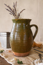 Antique French green glazed redware pitcher with honey yellow glazed interior, hand-thrown terracotta body, darkened base, and old rim chip near handle.