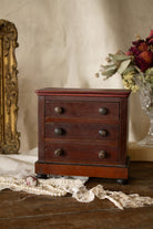 Antique French miniature veneered tabletop chest of drawers with three working drawers, warm reddish brown wood, turned knobs, bun feet, and paper label fragment