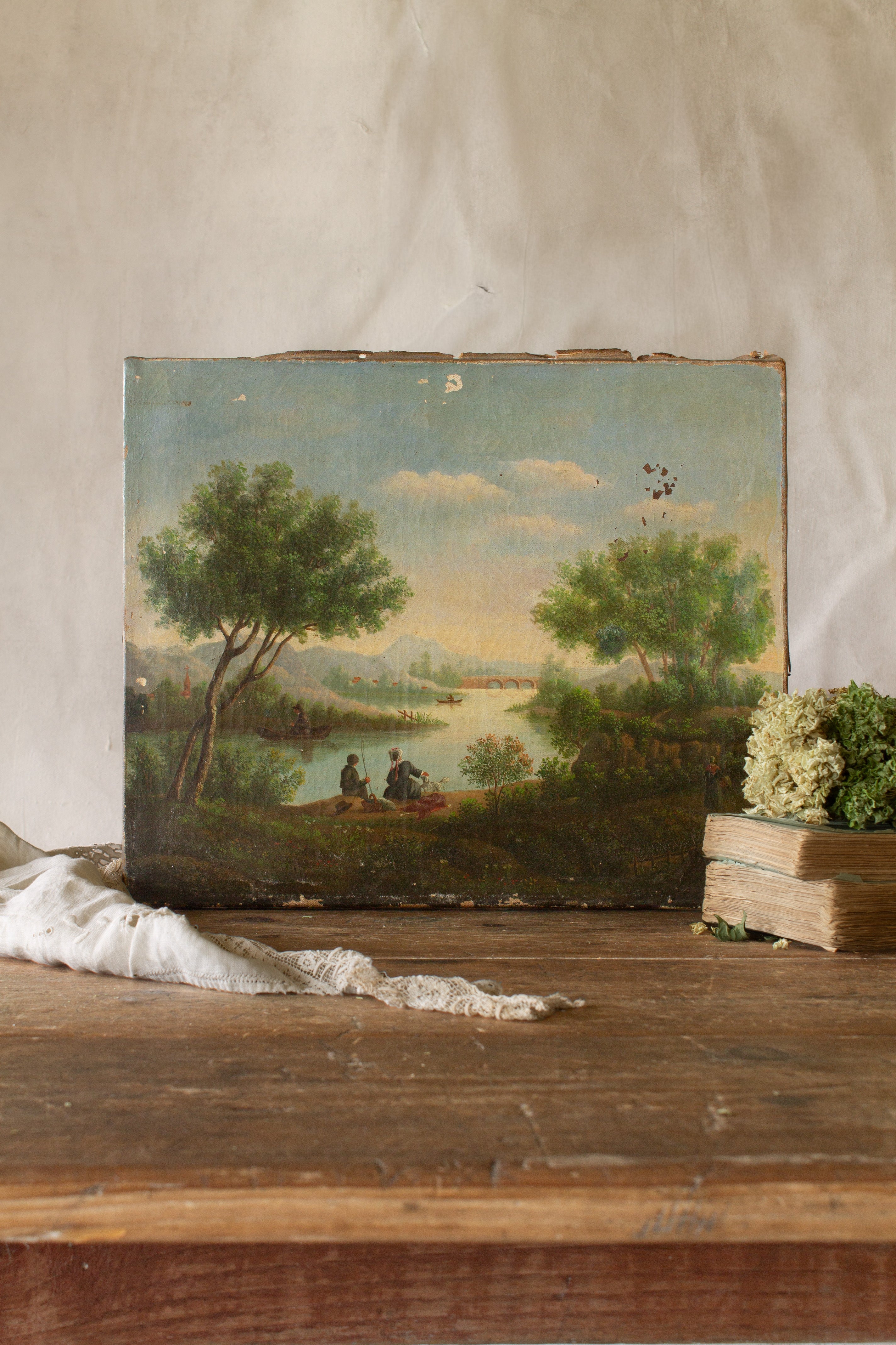Antique French oil landscape signed Lantonnet with riverside figures, boats, trees, distant hills, and aged canvas surface.