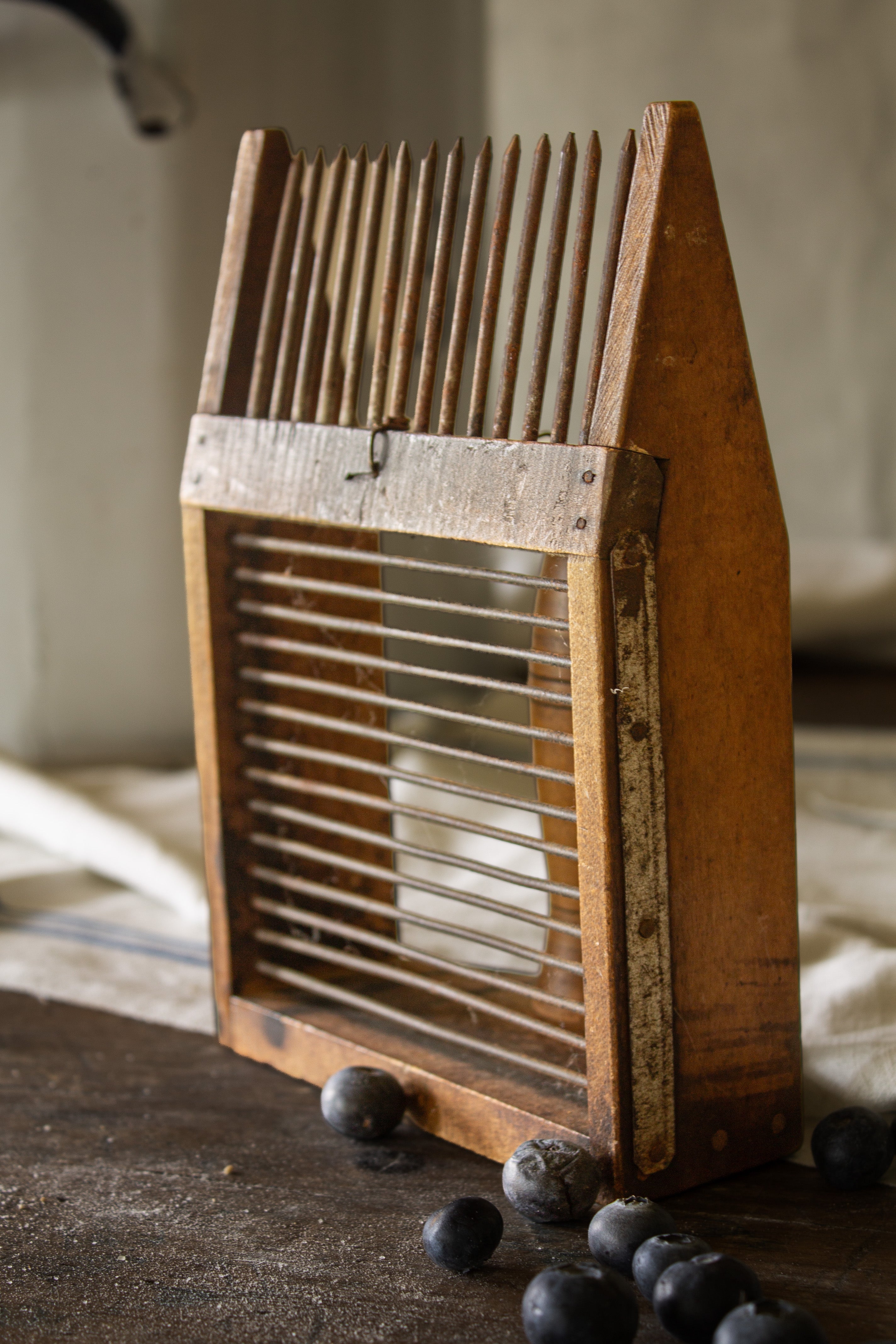 Back view of an antique French peigne à myrtilles showing the iron teeth, horizontal gathering rods, and wooden frame.