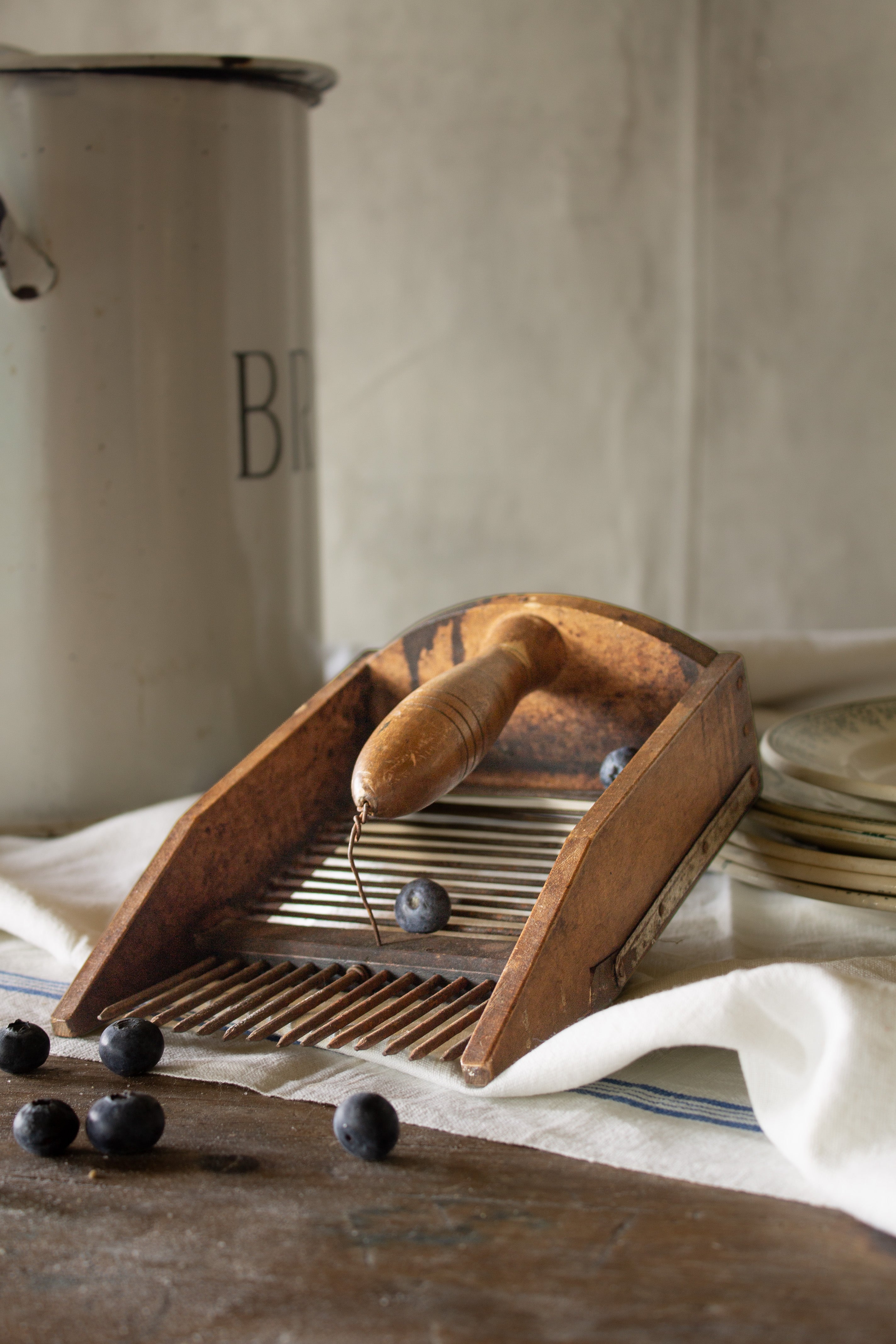 Antique French berry comb shown at an angle with its wooden handle, iron comb teeth, and metal rods visible.