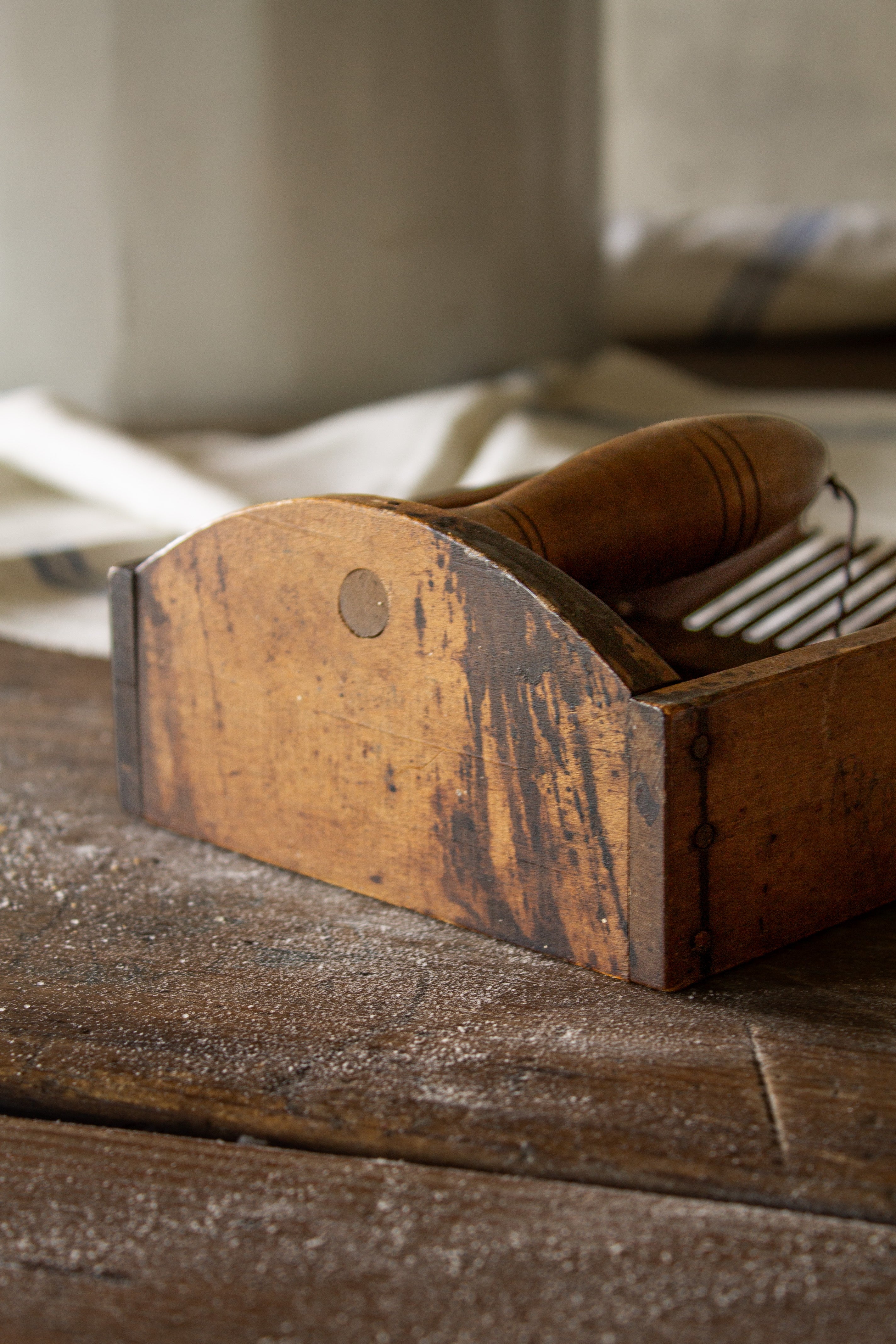 Close view of the base and worn wooden frame and aged surface on an antique French peigne à myrtilles berry comb.