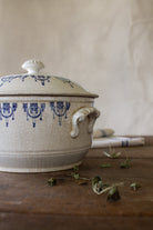 Antique French Saint-Uze style blue and white lidded tureen with cobalt stamped pattern, crackled cream glaze, worn handles, and flower-form finial.
