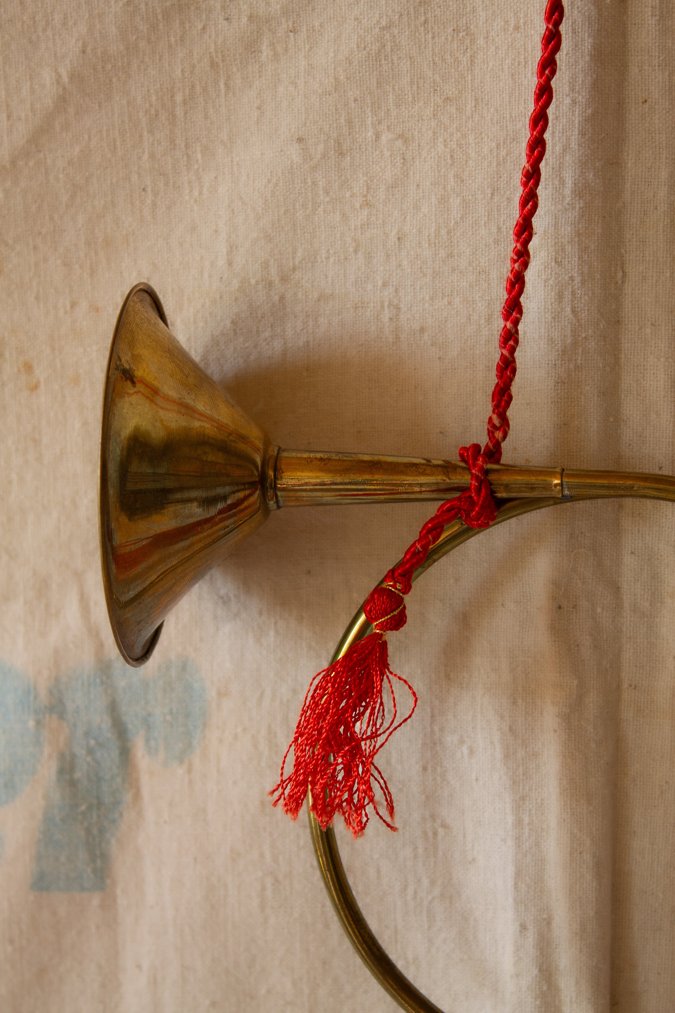 Vintage lightweight brass hunt-style wall hanging with red braided cord, tassels, circular brass horn form, and decorative seasonal styling