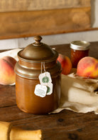 Vintage copper-plated lidded kitchen canister with domed lid and warm aged patina, styled with tea bags and peaches.