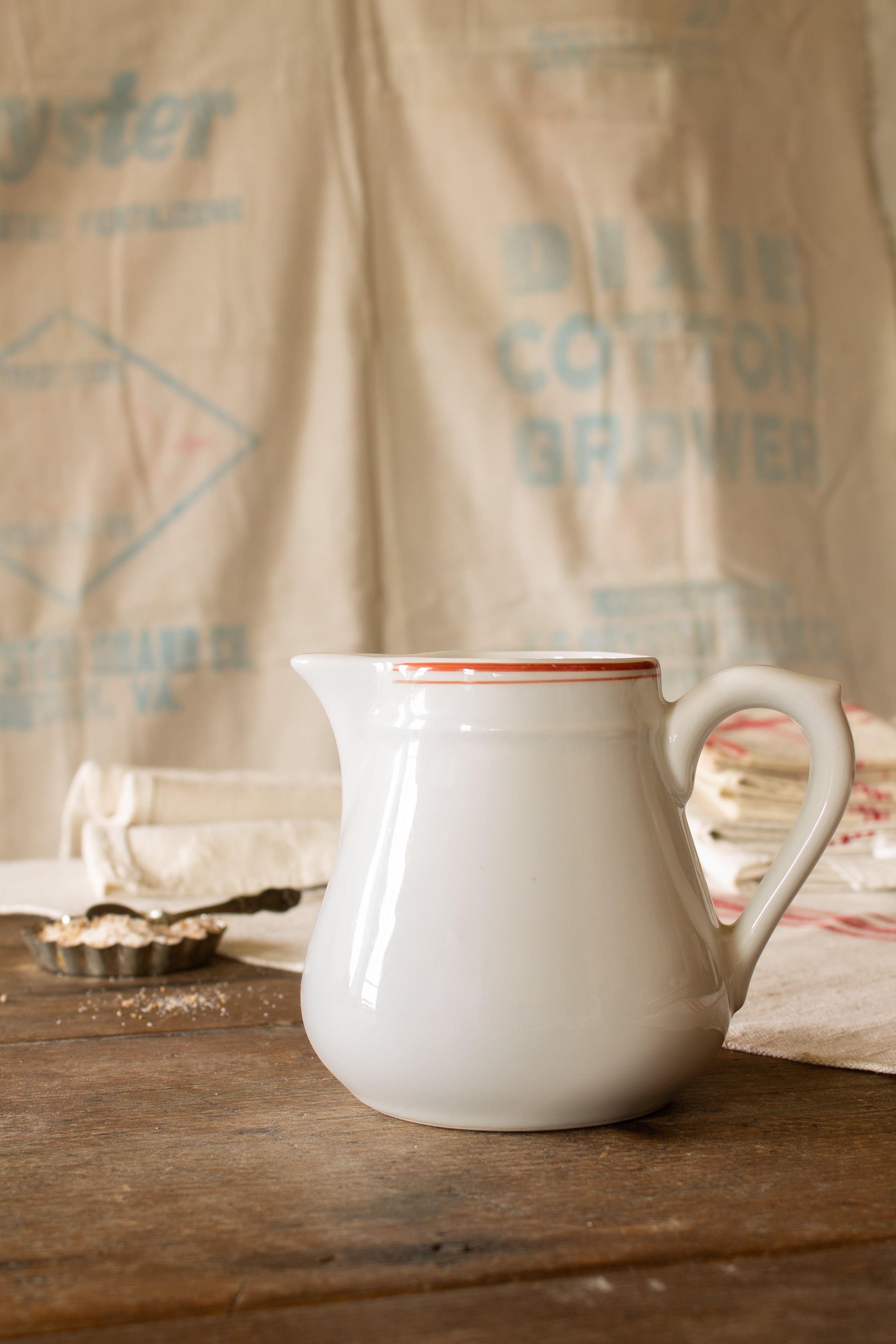 Vintage French APILCO porcelain creamer with red band detail, white body, shaped handle, and pouring spout.