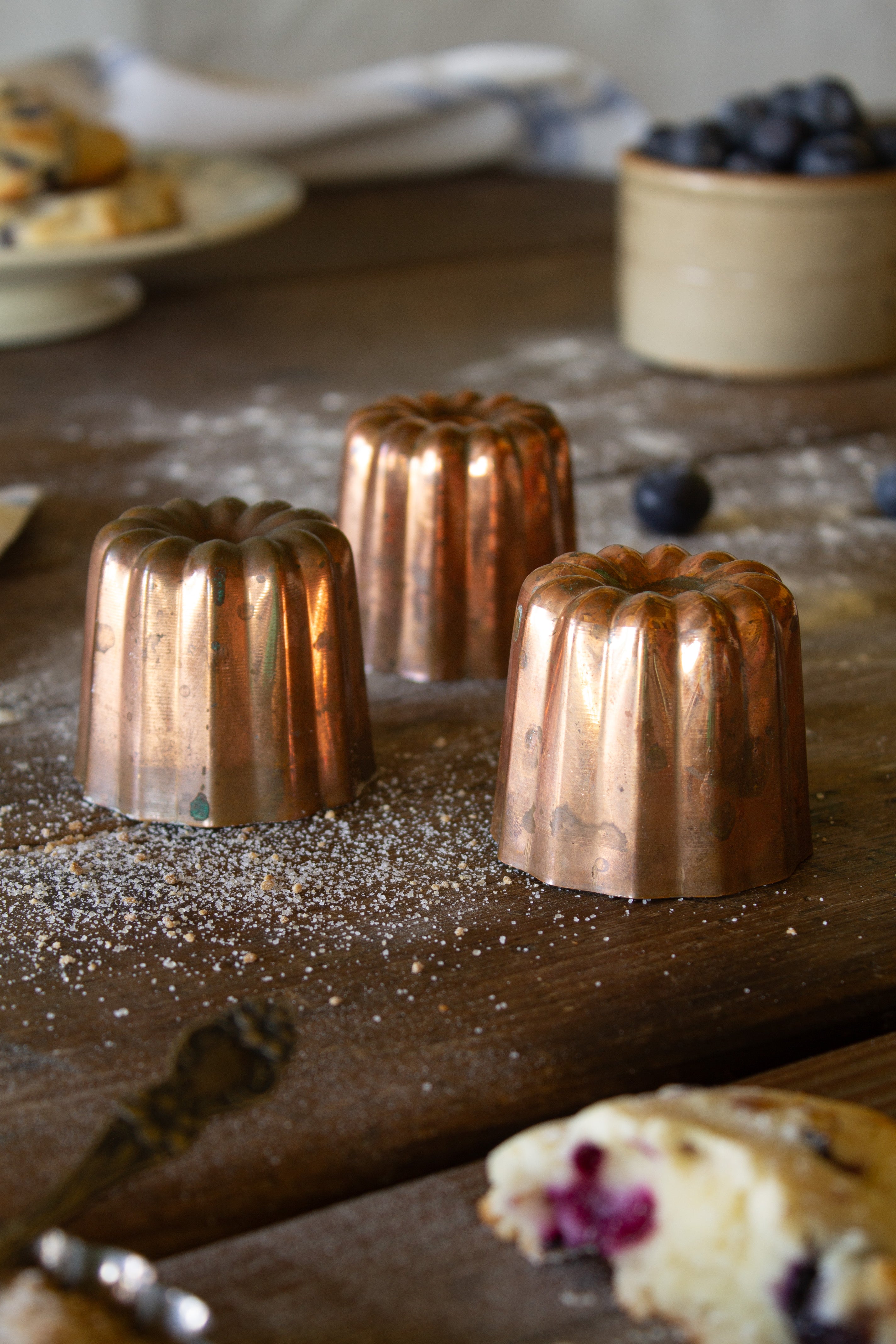 Set of three vintage French copper canelé molds with fluted sides, aged patina, and silver-colored lined interiors.