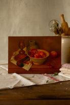 Vintage French moody still life painting on wood panel with peaches, cherries, pottery, copper candlestick, and red-striped kitchen cloth.