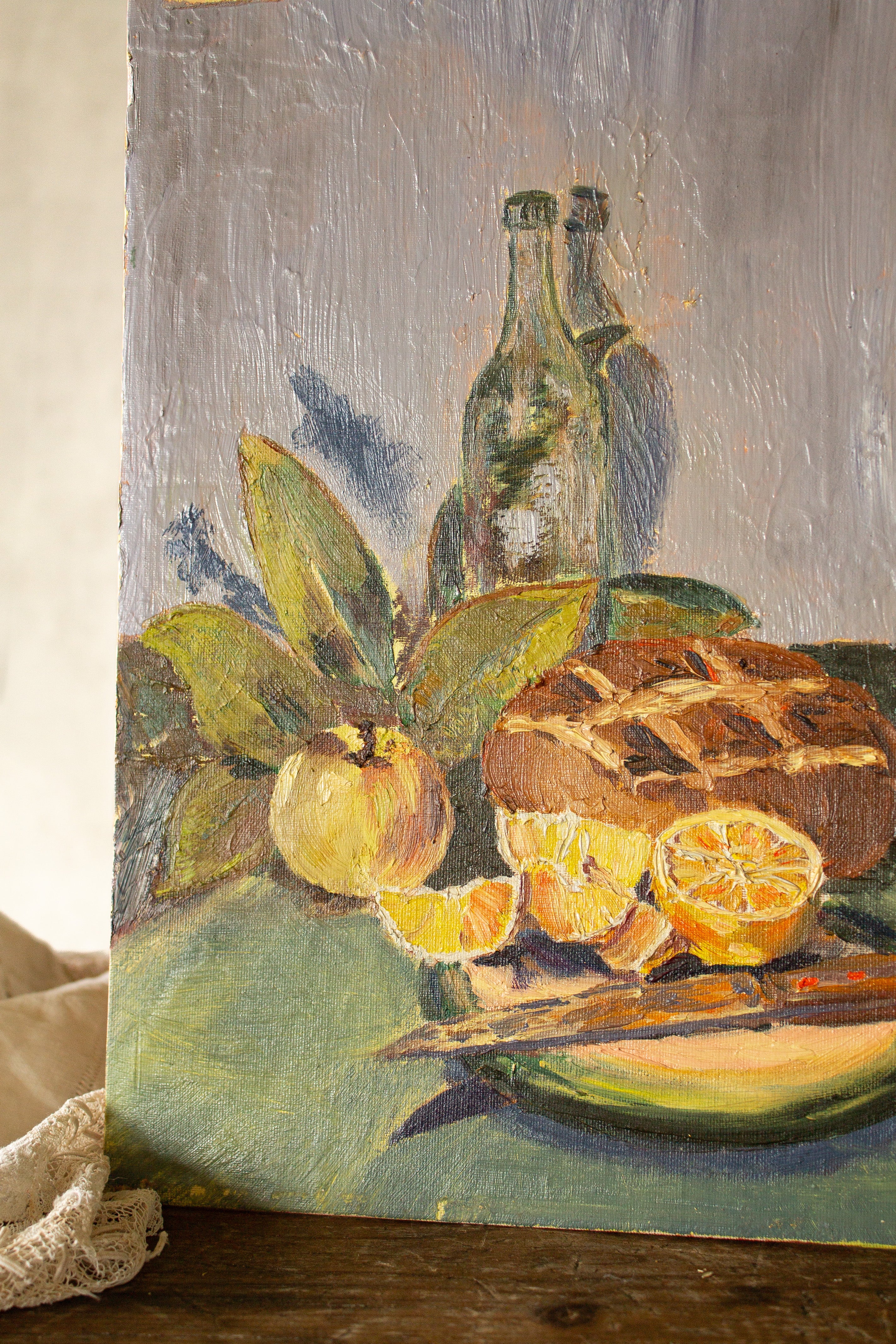 Close detail of textured brushwork on a vintage French still life painting with orange citrus, green leaves, and warm yellow highlights.